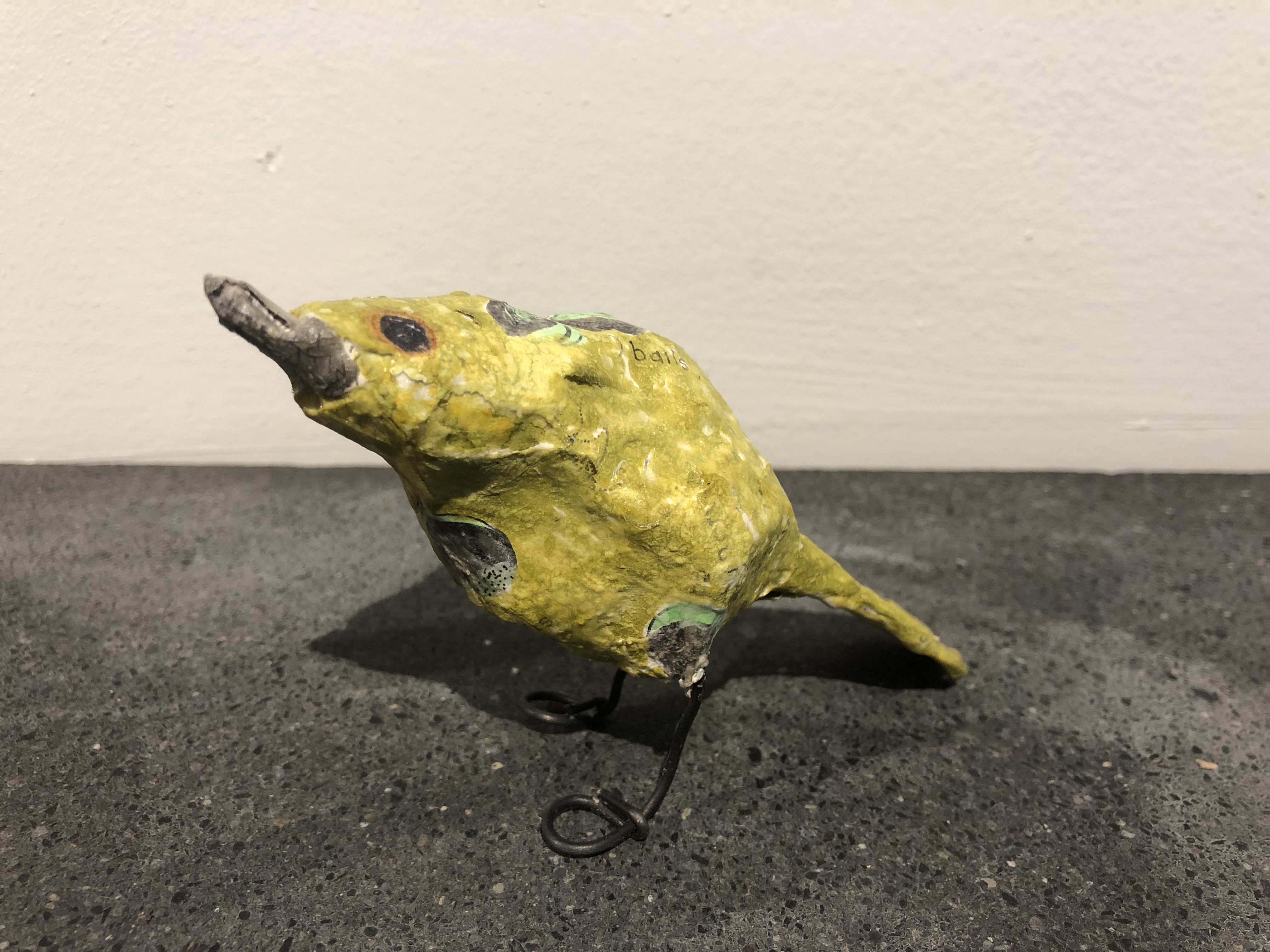 Yellow bird with grey beak hunched down.